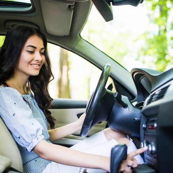 Image of a woman playing with the radio in her car Image of a woman playing with the radio in her car