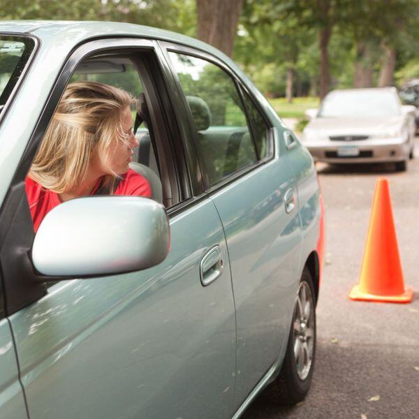 A teenage girl practices backing up a car
